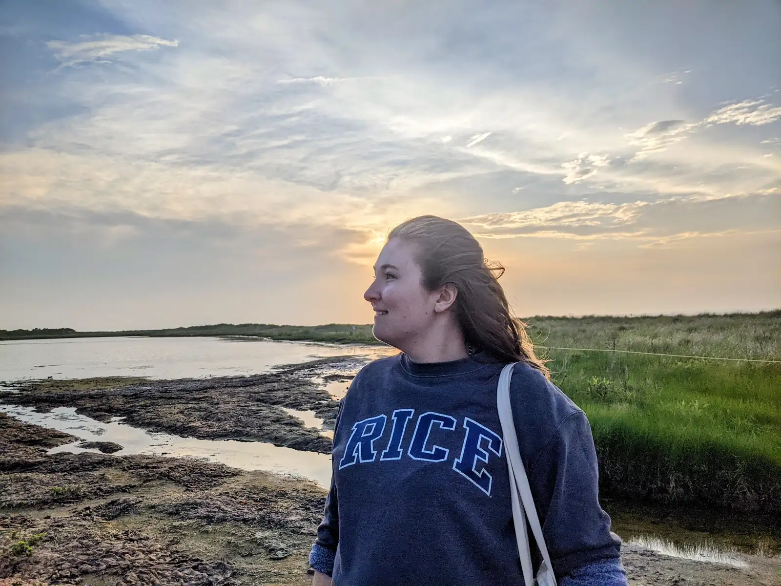 Dr. Anna Reed at the beach looking out over a sunset.