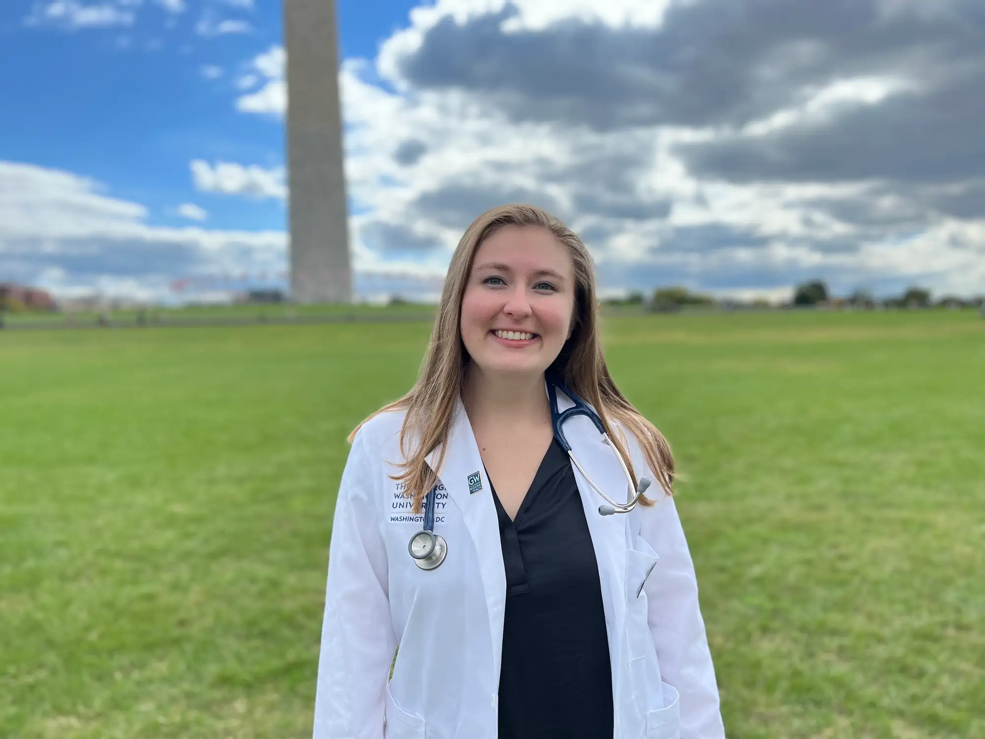Dr. Anna Reed dressed in a white coat standing in front of the Washington Monument.
